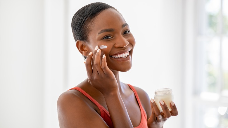 beautiful dark skinned woman applying moisturizer