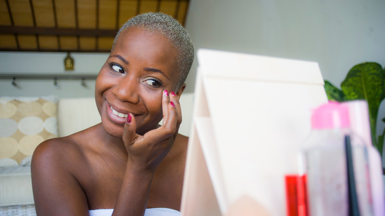 african american woman applying primer before makeup