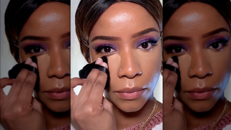 woman blending concealer with powder puff