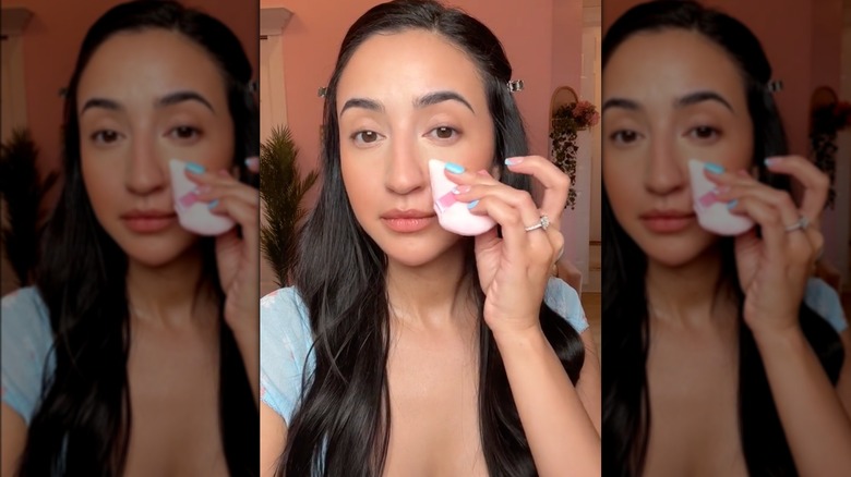 woman blending concealer with powder puff