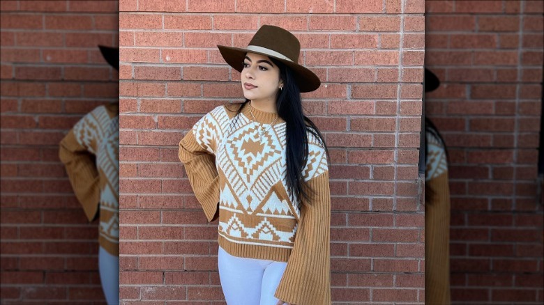 Individual in a tan and white sweater with bell sleeves