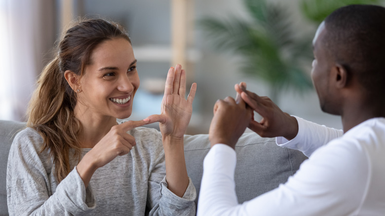 Two people smiling and speaking a signed language