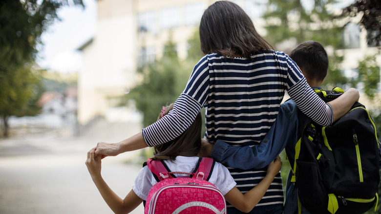 Protective mother walking kids to school