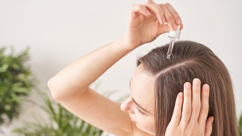 Woman applies oil to scalp