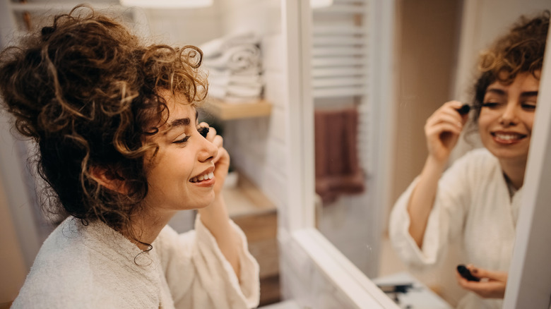 woman applying mascara in mirror