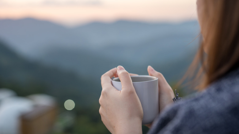 woman holding cup looking out 