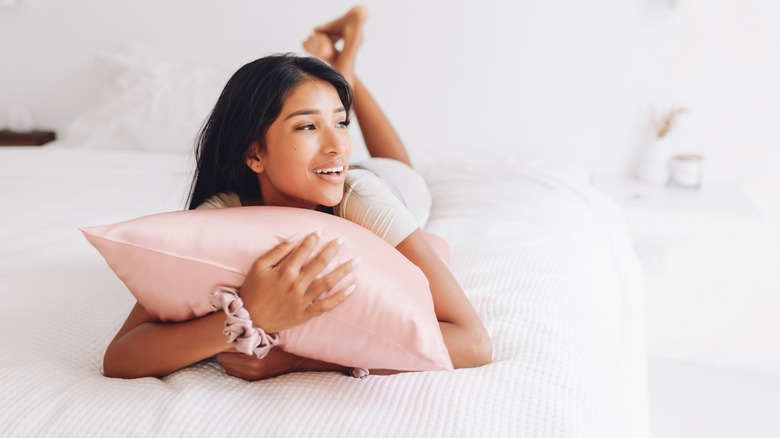 woman hugging pillow with silk pillowcase