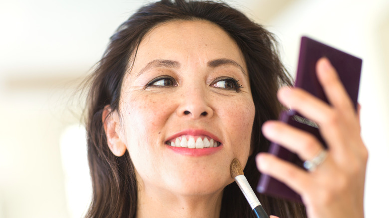 Woman applying concealer with brush