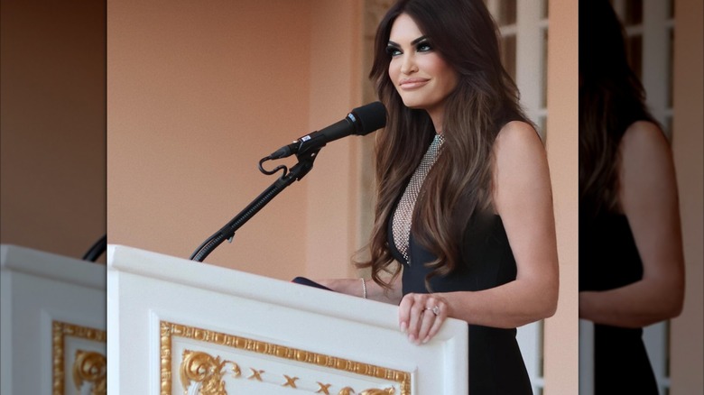 Kimberly Guilfoyle at a podium while wearing a black dress with chainmail detail