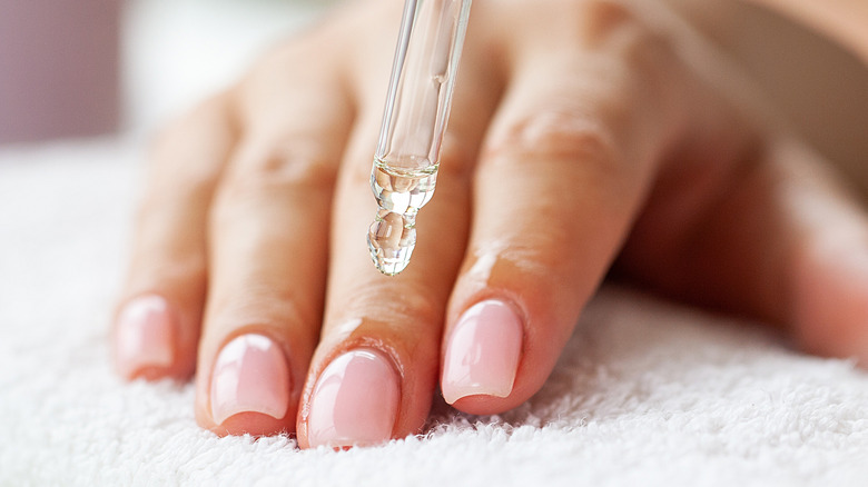 Hands applying oil to nails