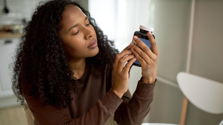 woman looking at vitamin bottle