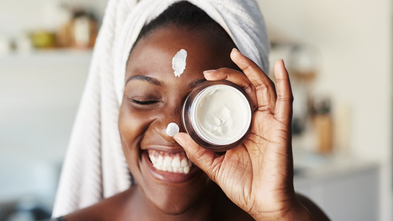 Woman holding container of face lotion