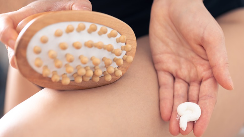 Person holding cellulite brush and cream