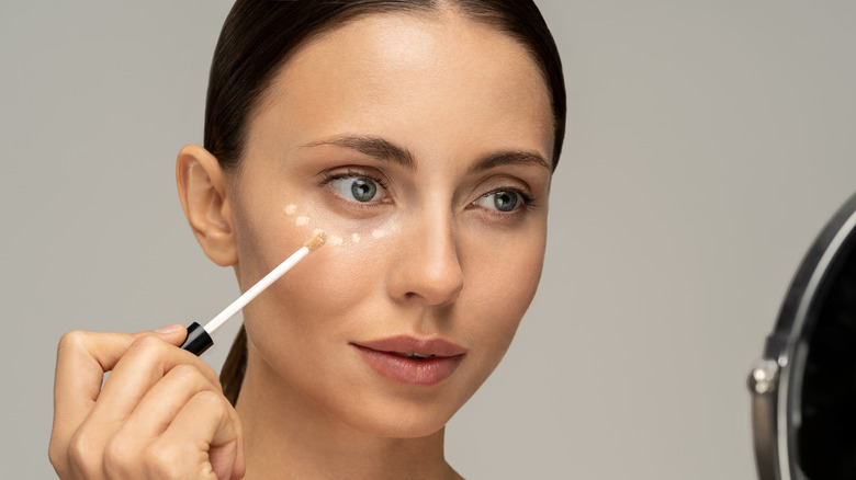 woman applying concealer under eyes