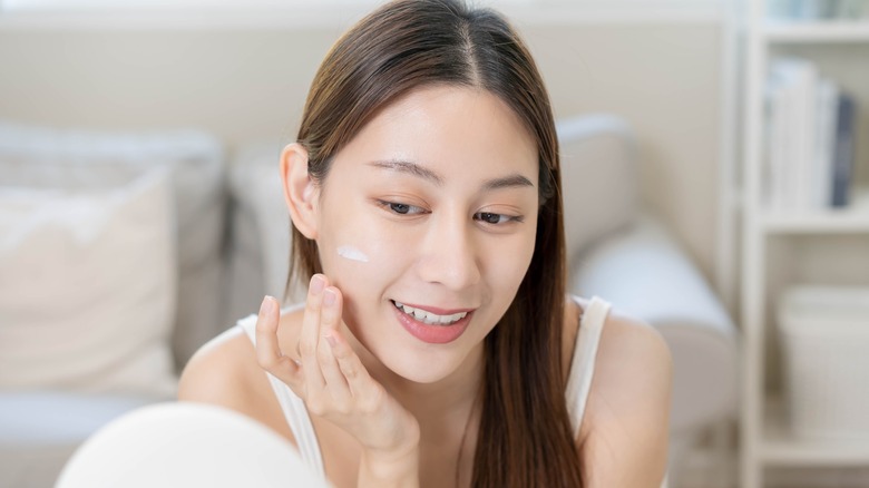 Woman putting on face cream 