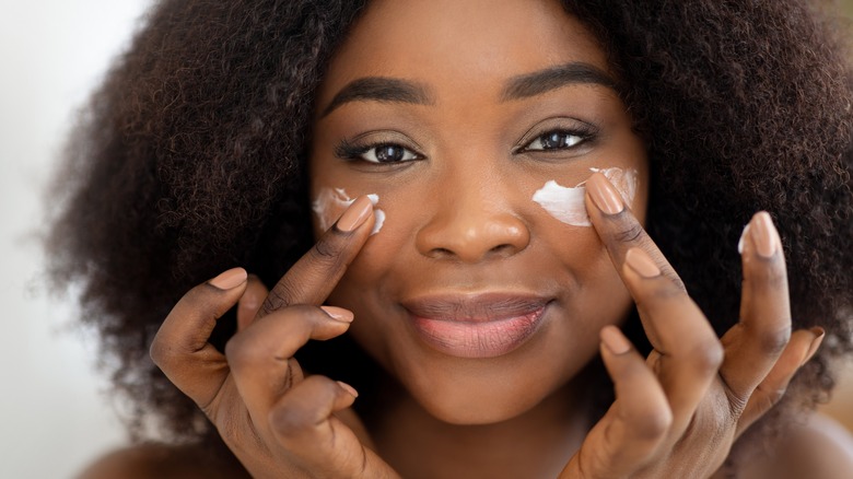 Woman applying eye cream to her under eyes