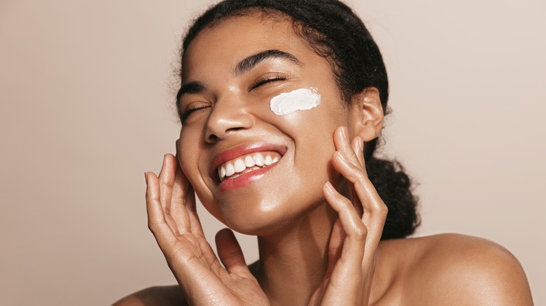 Smiling woman putting on beauty cream