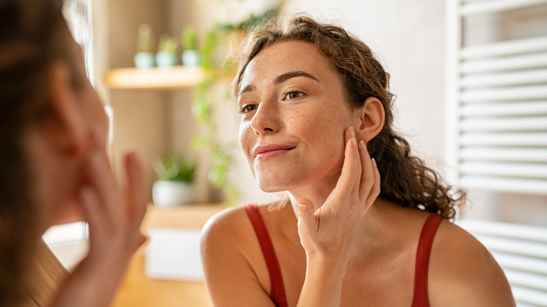 Woman looking at her skin in the mirror 