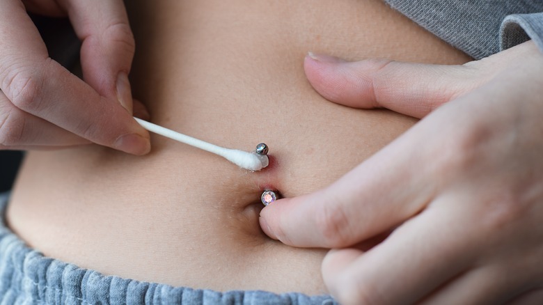 Person cleaning their belly button piercing