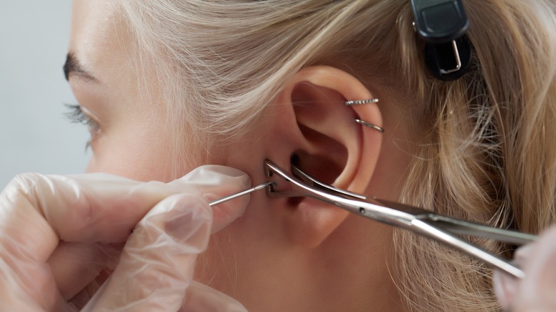 woman getting tragus ear piercing