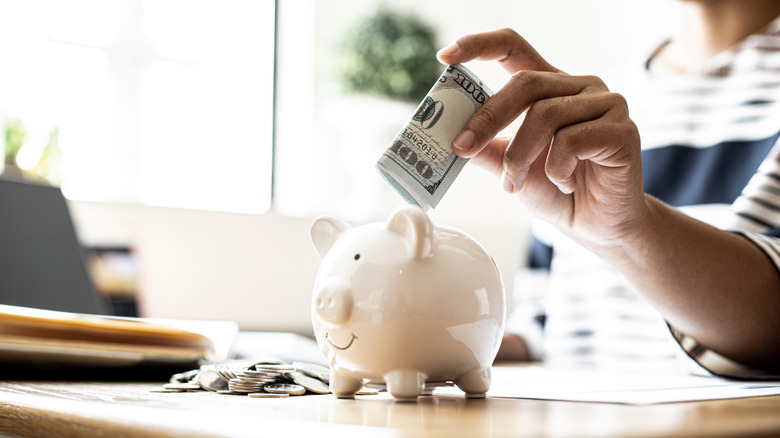 Woman putting money into her piggy bank