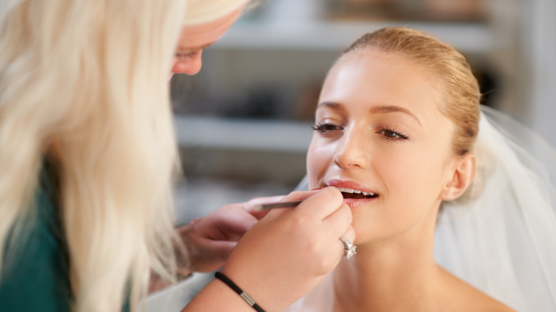 Makeup artist putting lipstick on a bride