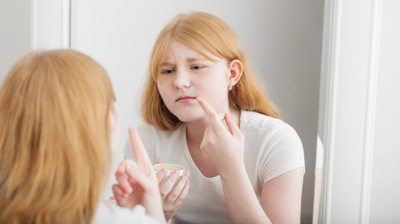 woman applying green concealer