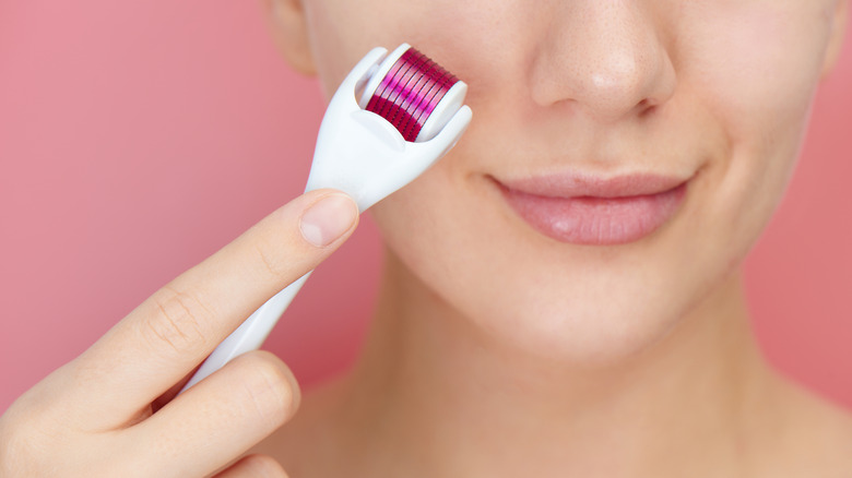 woman using a dermaroller on her cheek