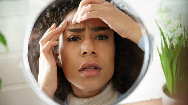 woman inspecting a pimple in the mirror