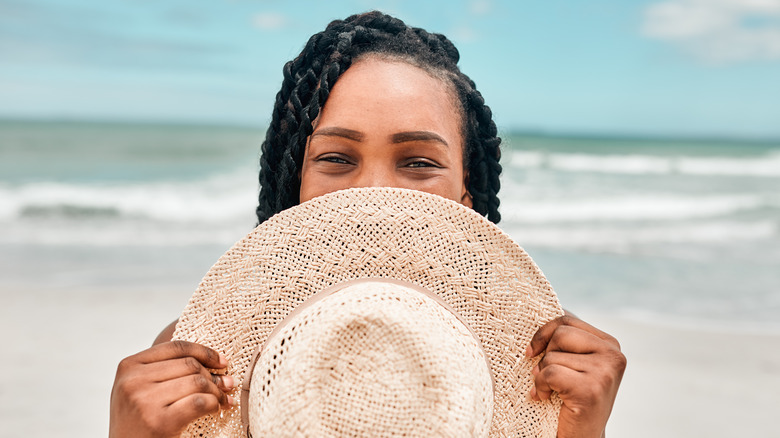 Woman holding hat at the beach