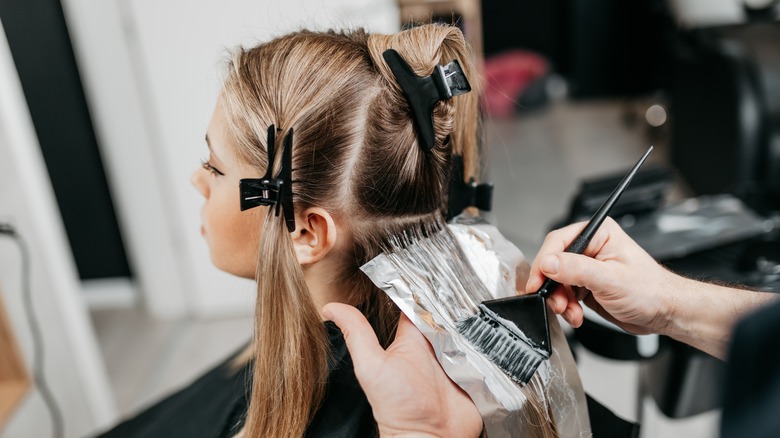 Woman getting hair dyed blonde at salon