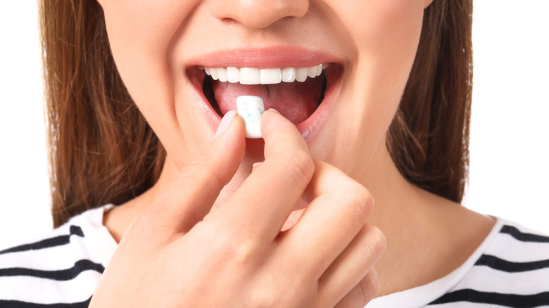 woman inserting gum into mouth