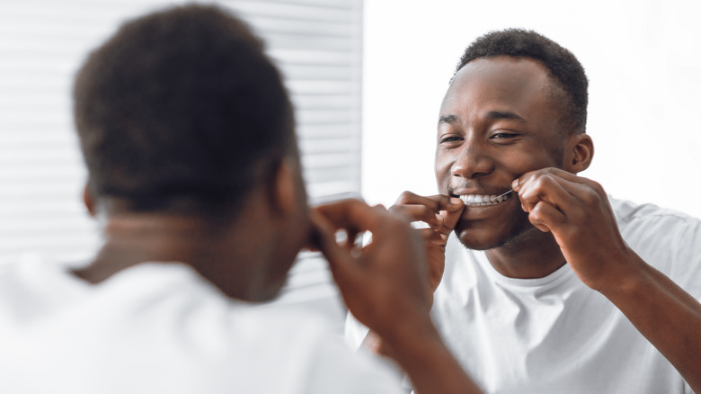 african american man flossing teeth in mirror