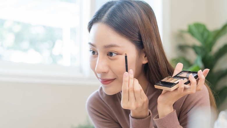 woman applying eyeshadow with brush