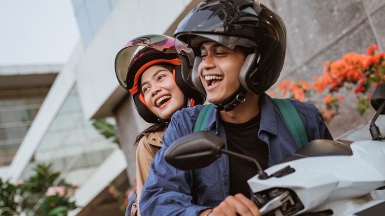 smiling man and woman on motorbike