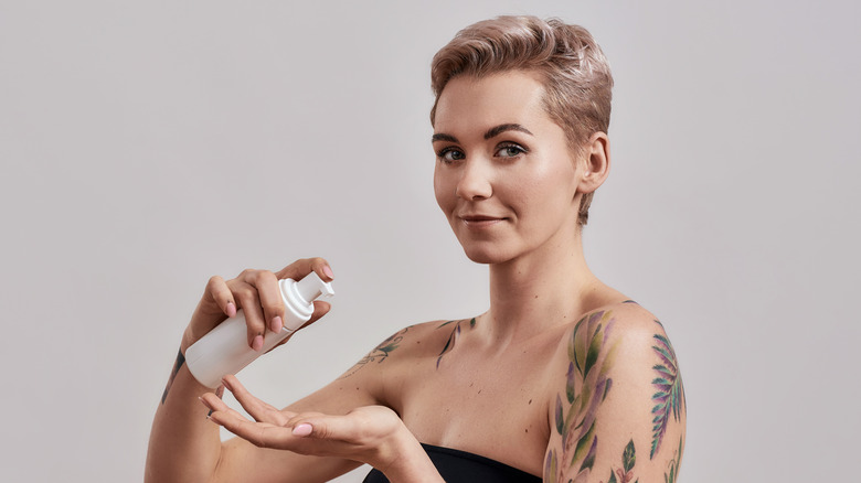 woman using face primer on tattoos