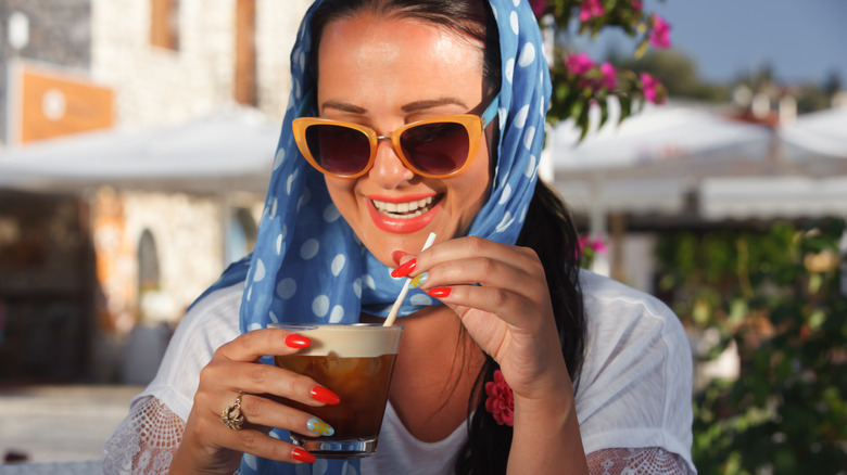 Woman in headscarf drinks espresso at outdoor cafe