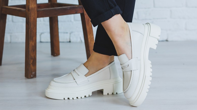 Woman wearing white loafers.