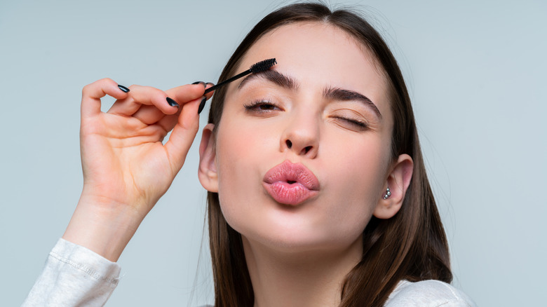 woman brushing out thick brows with spoolie