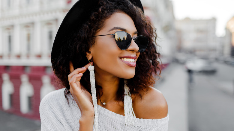 Woman smiling with sunglasses and long earrings
