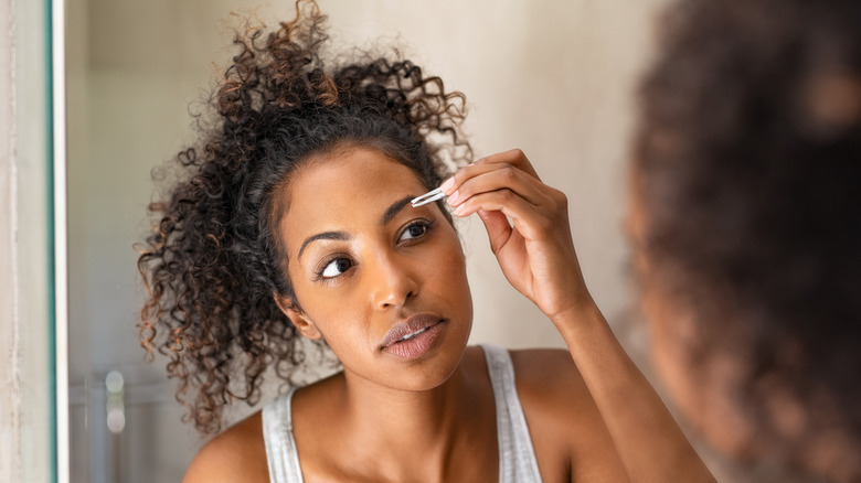 woman tweezing her brows