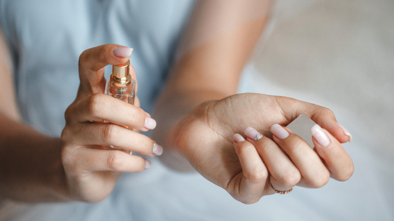 woman spraying perfume on wrist