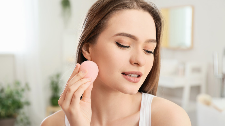 woman using a beauty sponge on her face