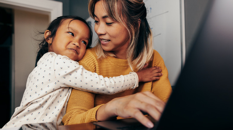 Little girl hugging mother in home office