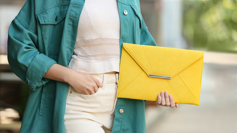 woman holding yellow envelope purse