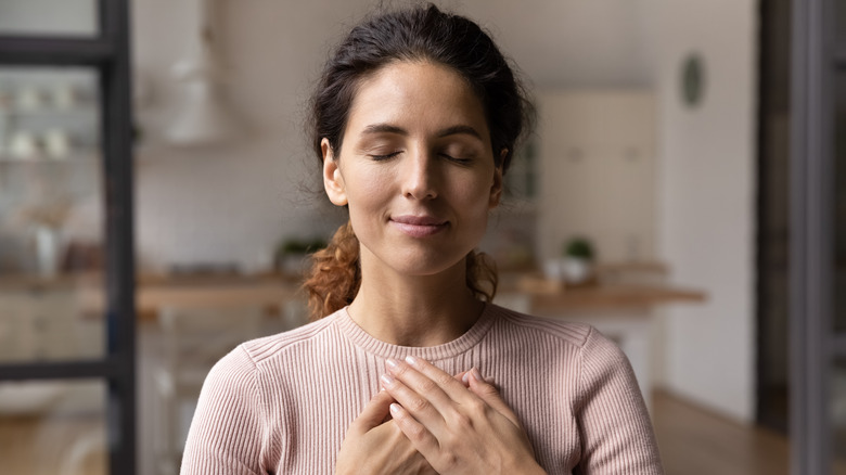 woman holding hands over heart 