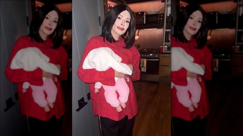 Patti Harrison dressed as Michael Jackson and holding a baby doll