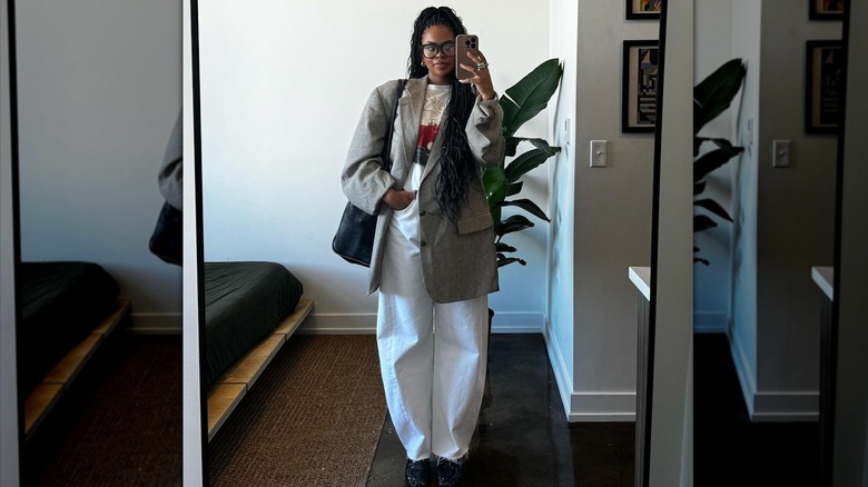 woman in barrel-leg jeans taking selfie