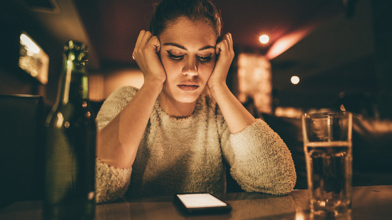 Woman sitting at a bar looking at phone