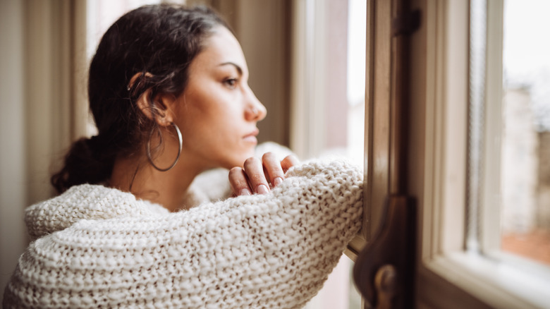 Worried person looking out window